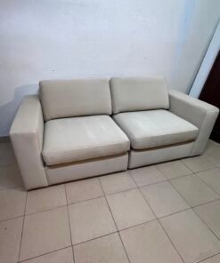 The KIVIK two-seater sofa is beige and features wide, low armrests.