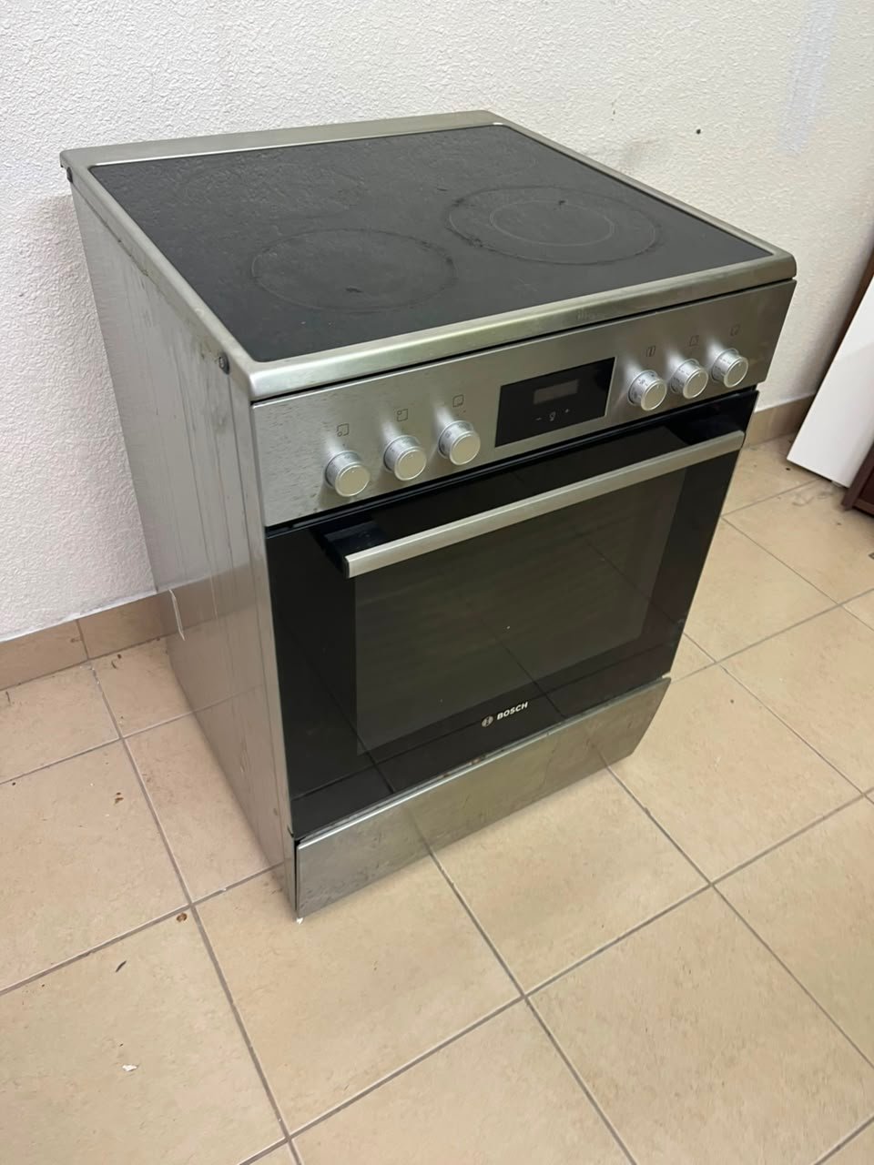 The image shows a freestanding Bosch electric cooker measuring 60x60 cm with a glass ceramic surface and built-in oven.
