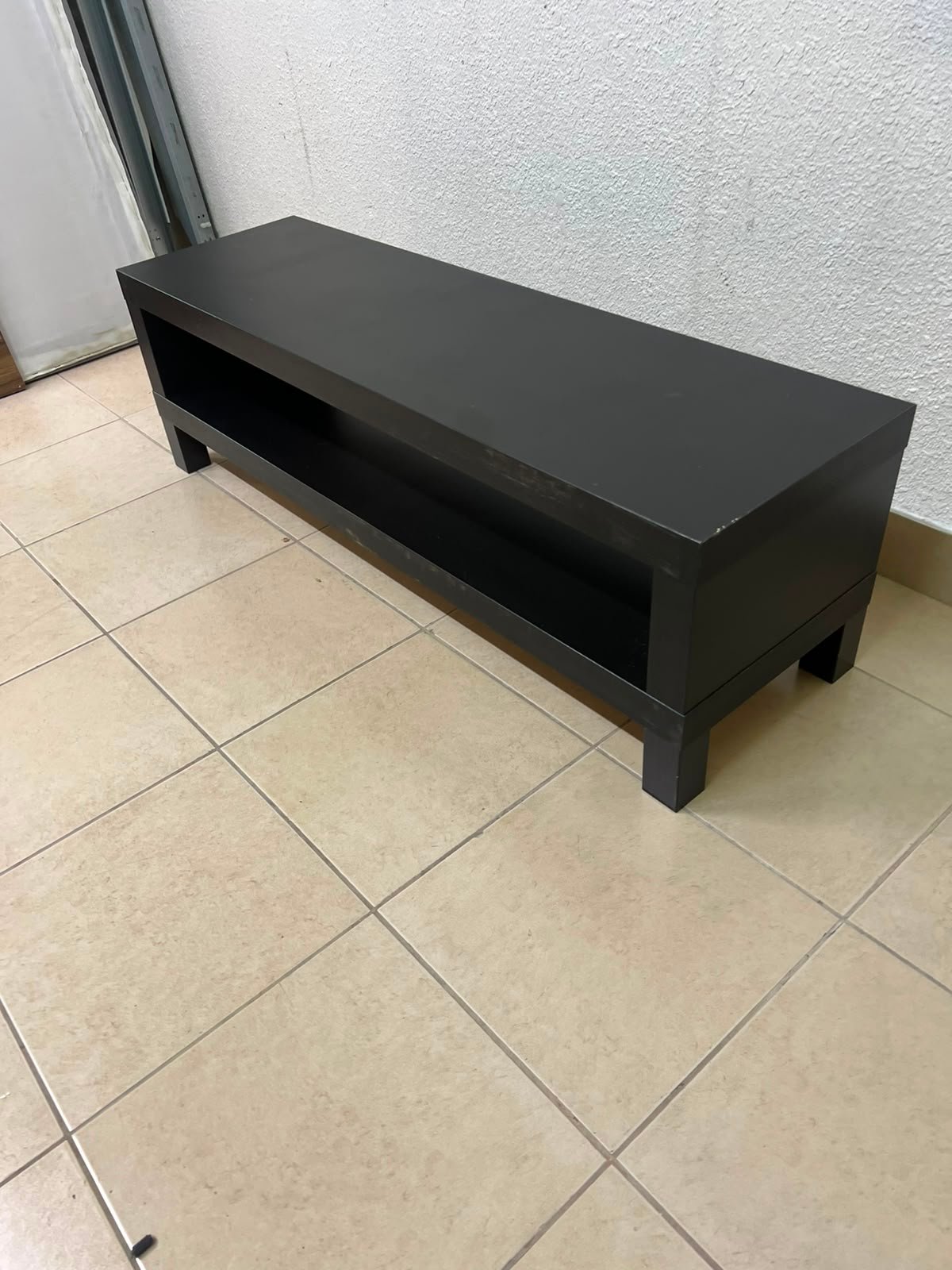 The image shows a TV stand from the IKEA LACK collection in black and brown.