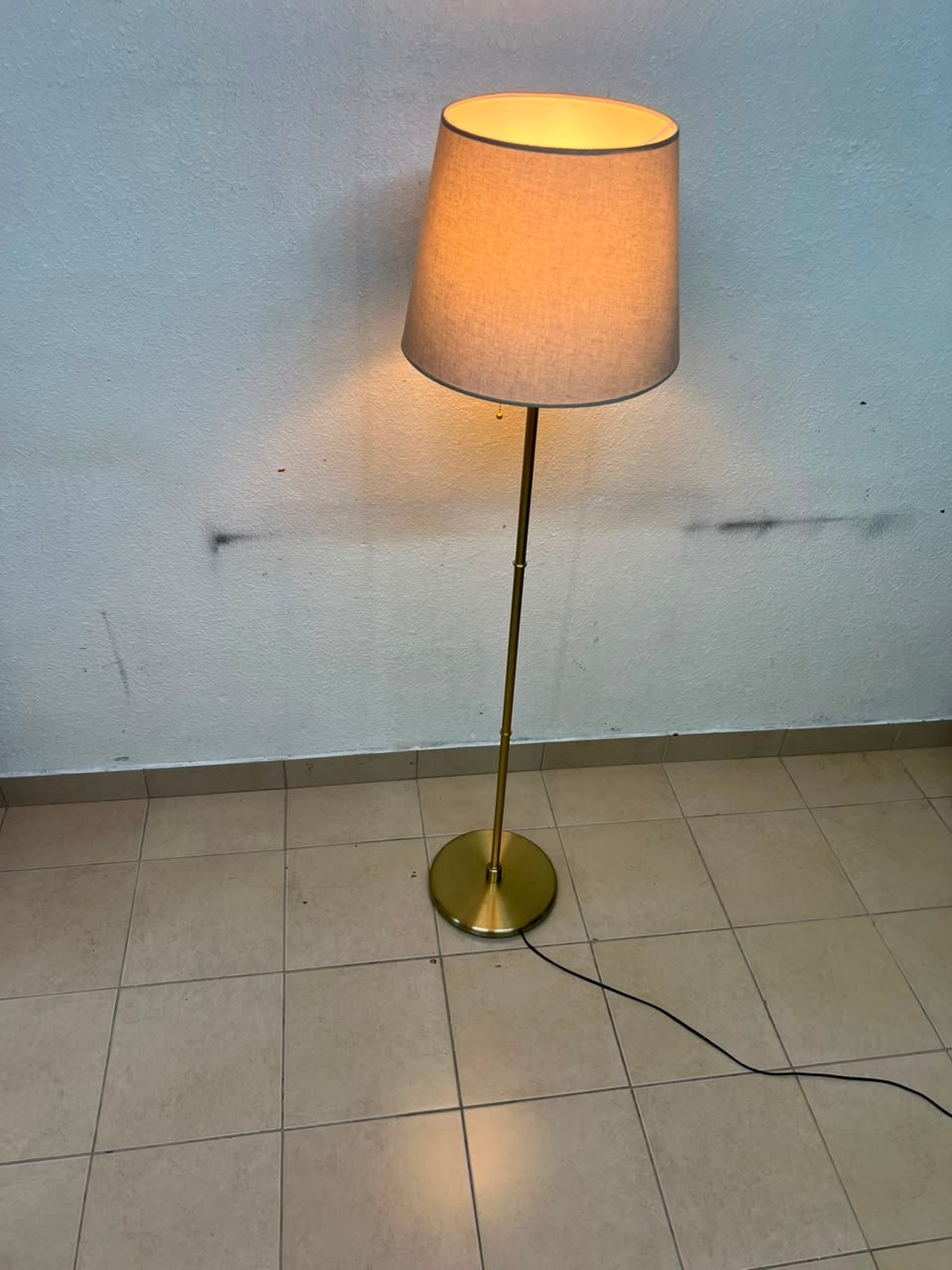A modern and elegant floor lamp (lampade) with a slim, copper-gold metal base and a warm fabric shade. - Image 3
