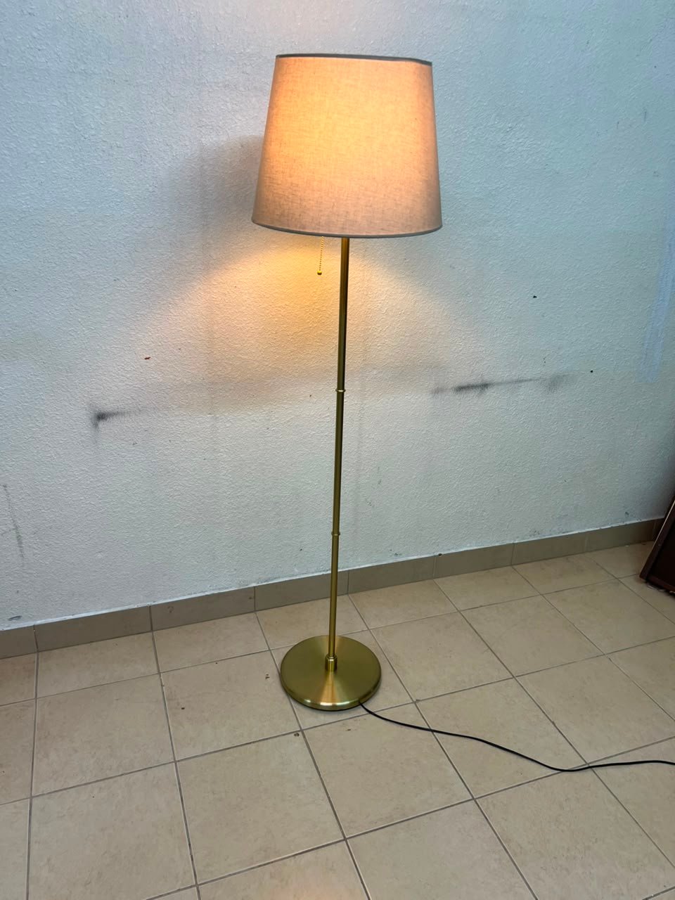 A modern and elegant floor lamp (lampade) with a slim, copper-gold metal base and a warm fabric shade. - Image 2