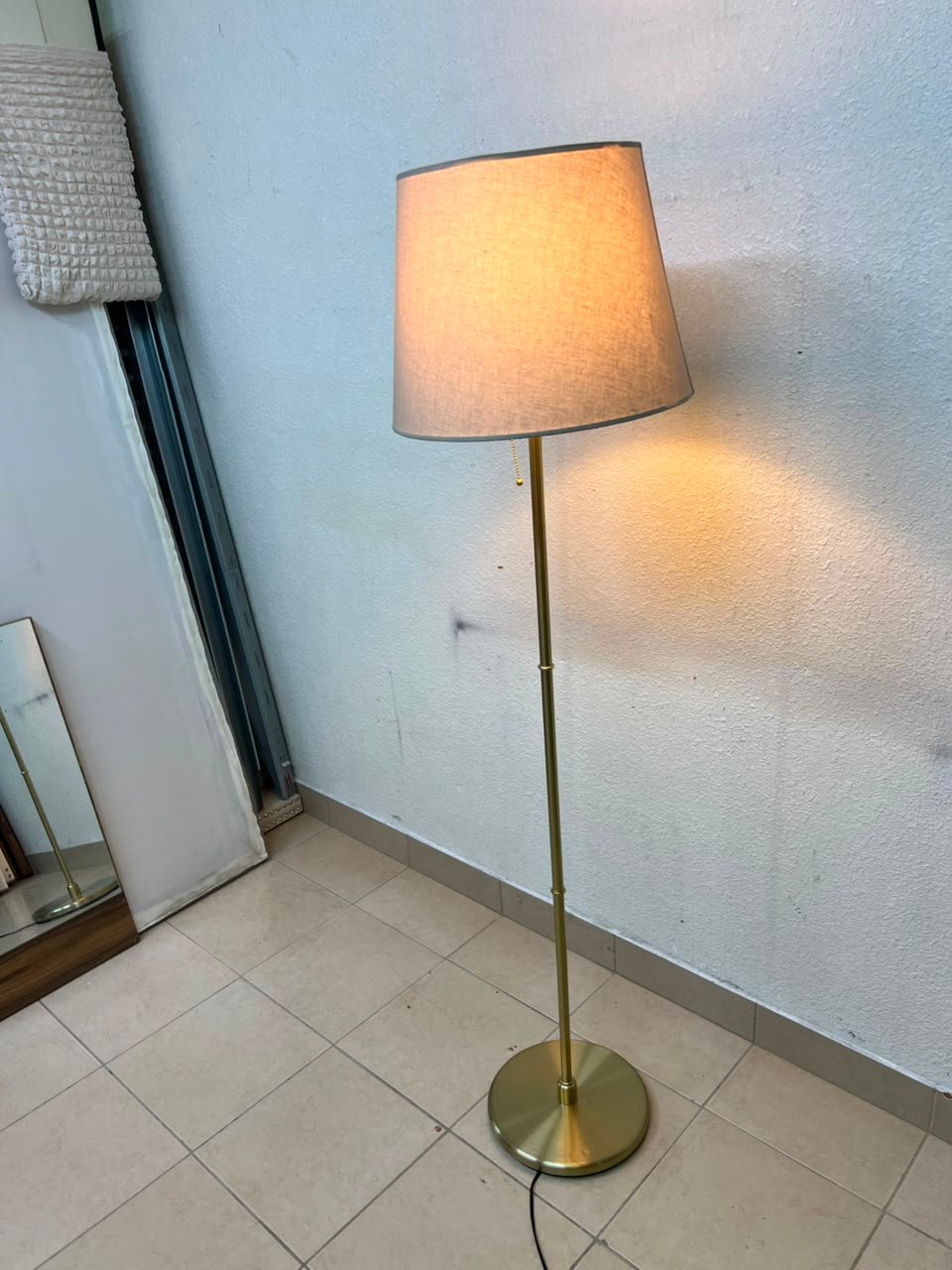 A modern and elegant floor lamp (lampade) with a slim, copper-gold metal base and a warm fabric shade. - Image 4