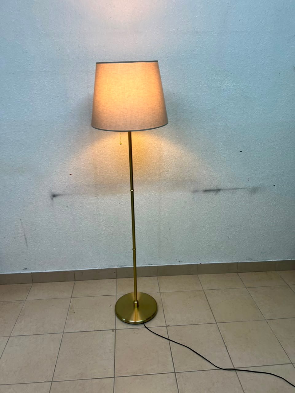 A modern and elegant floor lamp (lampade) with a slim, copper-gold metal base and a warm fabric shade. - Image 8