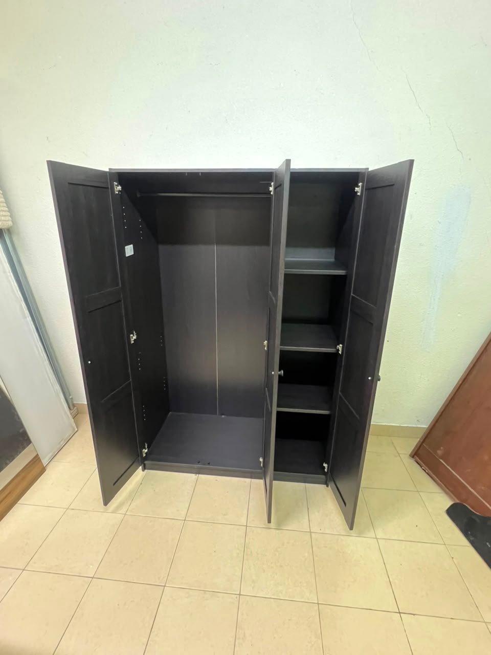 The RAKKESTAD wardrobe from IKEA has three doors and comes in a black-brown color, measuring 117x176 cm. - Image 4