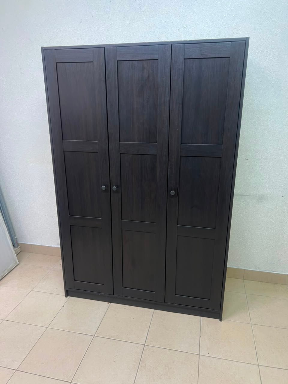 The RAKKESTAD wardrobe from IKEA has three doors and comes in a black-brown color, measuring 117x176 cm. - Image 2