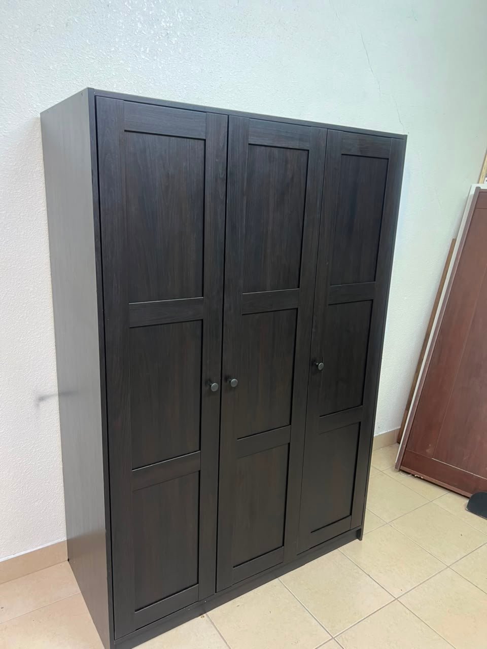 The RAKKESTAD wardrobe from IKEA has three doors and comes in a black-brown color, measuring 117x176 cm.