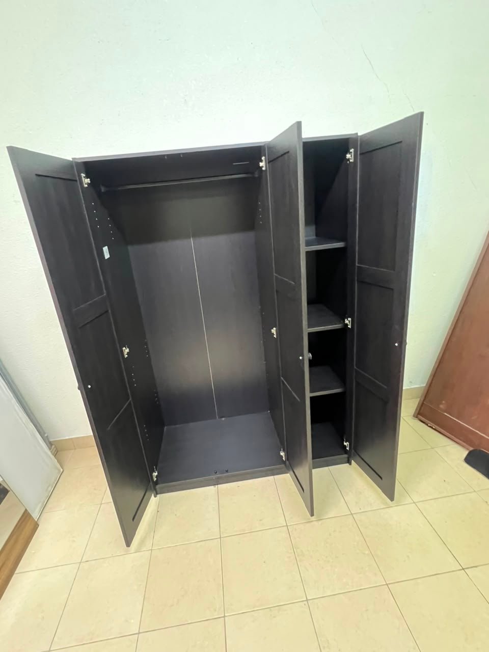 The RAKKESTAD wardrobe from IKEA has three doors and comes in a black-brown color, measuring 117x176 cm. - Image 5