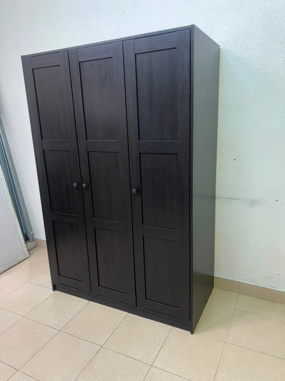 The RAKKESTAD wardrobe from IKEA has three doors and comes in a black-brown color, measuring 117x176 cm. - Image 10