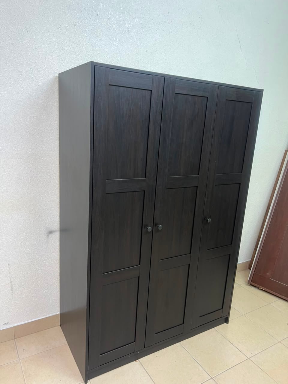 The RAKKESTAD wardrobe from IKEA has three doors and comes in a black-brown color, measuring 117x176 cm. - Image 9