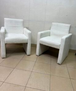 A modern white boucle fabric armchair, featuring an elegant base with flat legs and textured fabric upholstery.