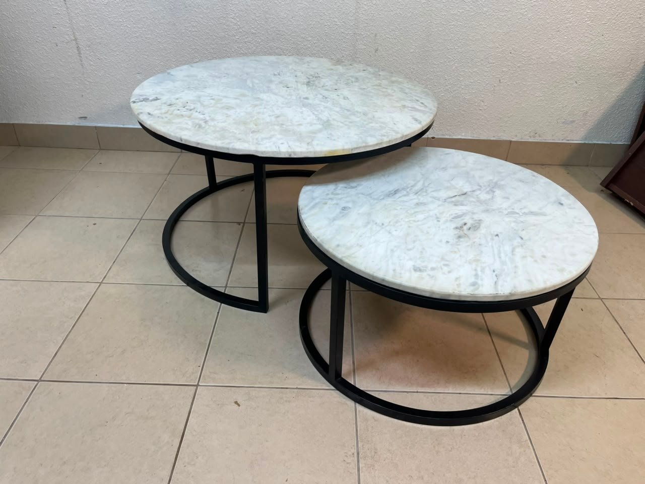 A set of nesting coffee tables (interlocking coffee tables) consisting of two pieces with a white marble top and a metal base.