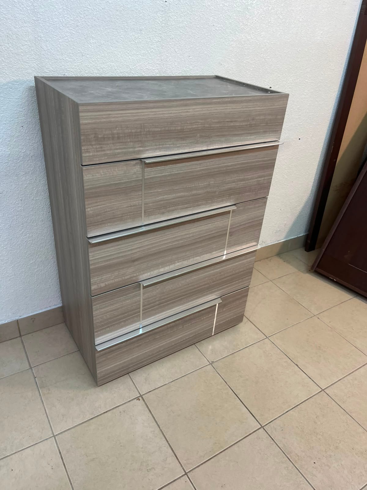 The Warner Chest of 5-Drawers from Homecentre features a beige and caramel walnut finish with distinct long metallic handles.