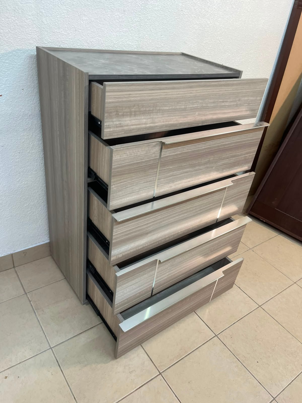 The Warner Chest of 5-Drawers from Homecentre features a beige and caramel walnut finish with distinct long metallic handles. - Image 10