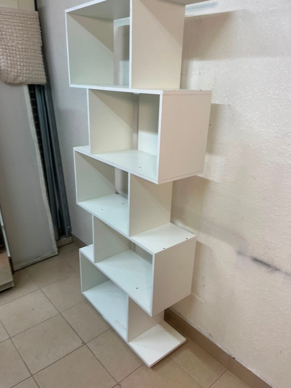 This white 5-tier geometric S-shaped bookshelf functions as an open display rack or room divider. - Image 7