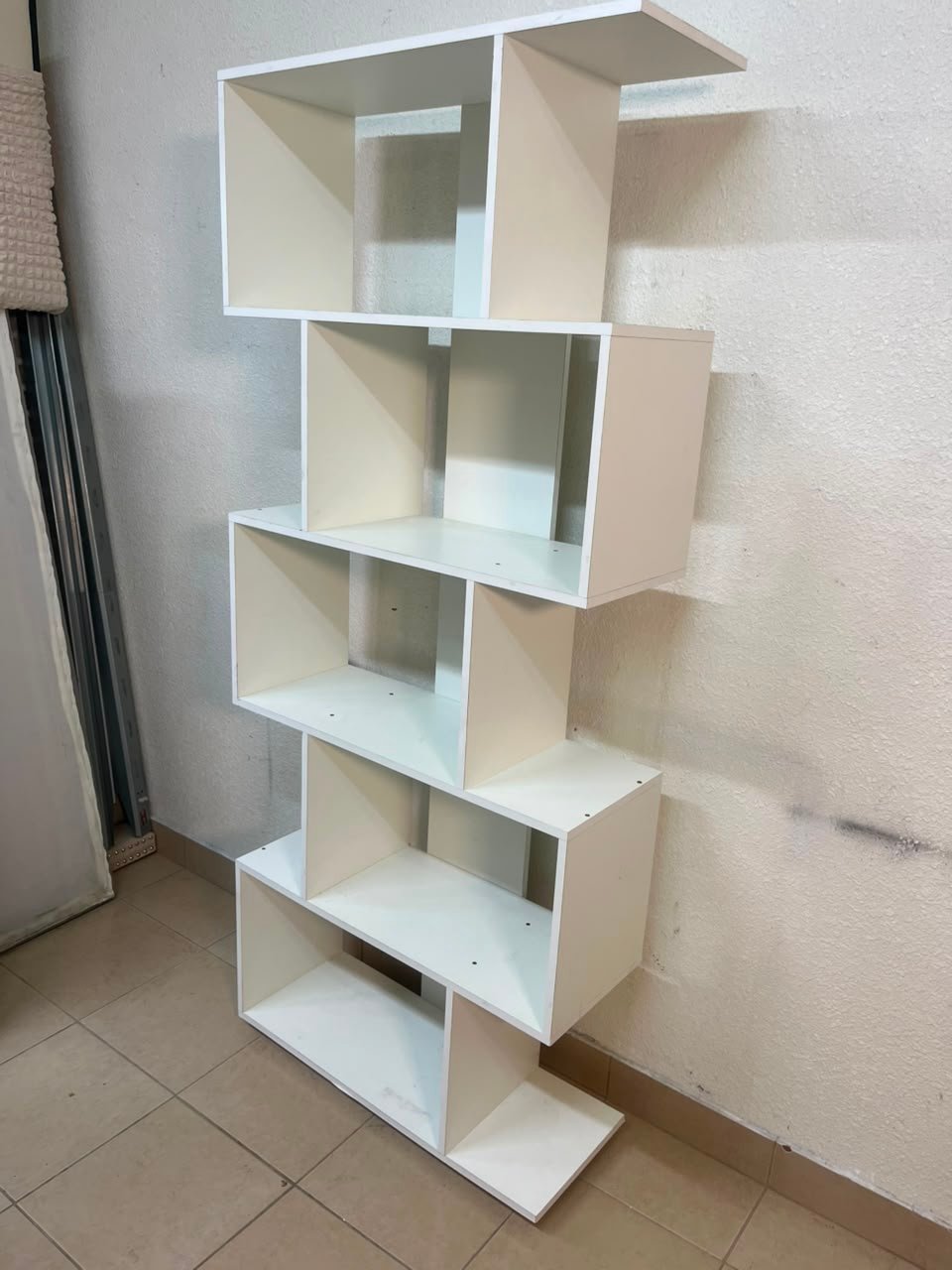 This white 5-tier geometric S-shaped bookshelf functions as an open display rack or room divider. - Image 6