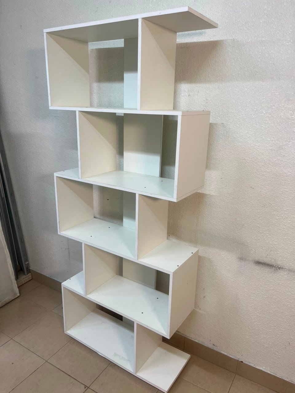 This white 5-tier geometric S-shaped bookshelf functions as an open display rack or room divider. - Image 9