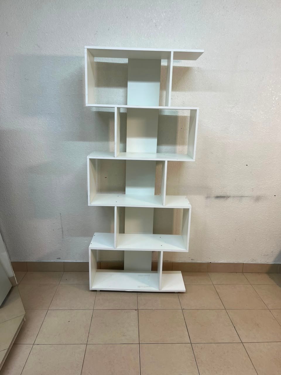 This white 5-tier geometric S-shaped bookshelf functions as an open display rack or room divider. - Image 13