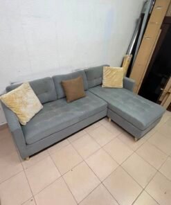 This is a three-seater corner sofa from IKEA in gray, featuring upholstered seat cushions and light-colored pointed wooden legs.