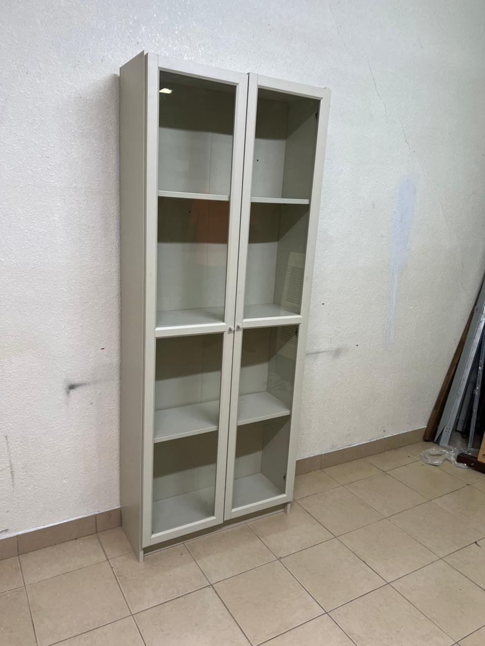 A bookcase with a glass door from IKEA, specifically from the BILLY/OXBERG series in white.
