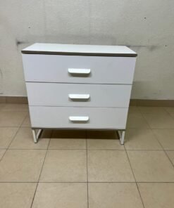 White chest of drawers with three drawers and metal legs with a connected frame.