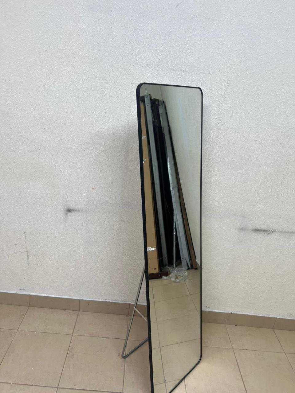 A tall, modern floor mirror featuring a slim black frame and elegant rounded corners.