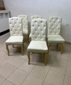 An elegant dining chair upholstered in beige fabric, featuring a high, comfortable back adorned with tufted buttons and delicate metal stud details. - Image 3