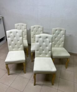 An elegant dining chair upholstered in beige fabric, featuring a high, comfortable back adorned with tufted buttons and delicate metal stud details. - Image 5