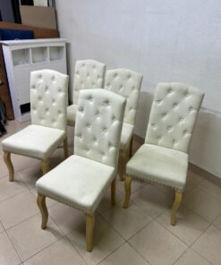 An elegant dining chair upholstered in beige fabric, featuring a high, comfortable back adorned with tufted buttons and delicate metal stud details. - Image 7