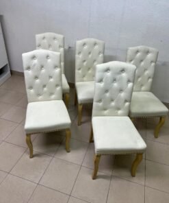 An elegant dining chair upholstered in beige fabric, featuring a high, comfortable back adorned with tufted buttons and delicate metal stud details. - Image 8