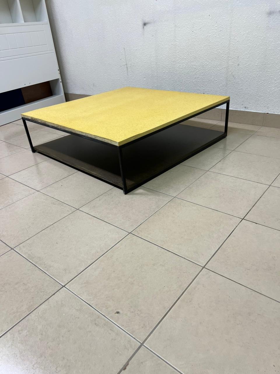 This is a square coffee table with an industrial design, featuring a black metal frame, a black pull-out drawer or lower shelf, and a light yellow wooden top. - Image 8