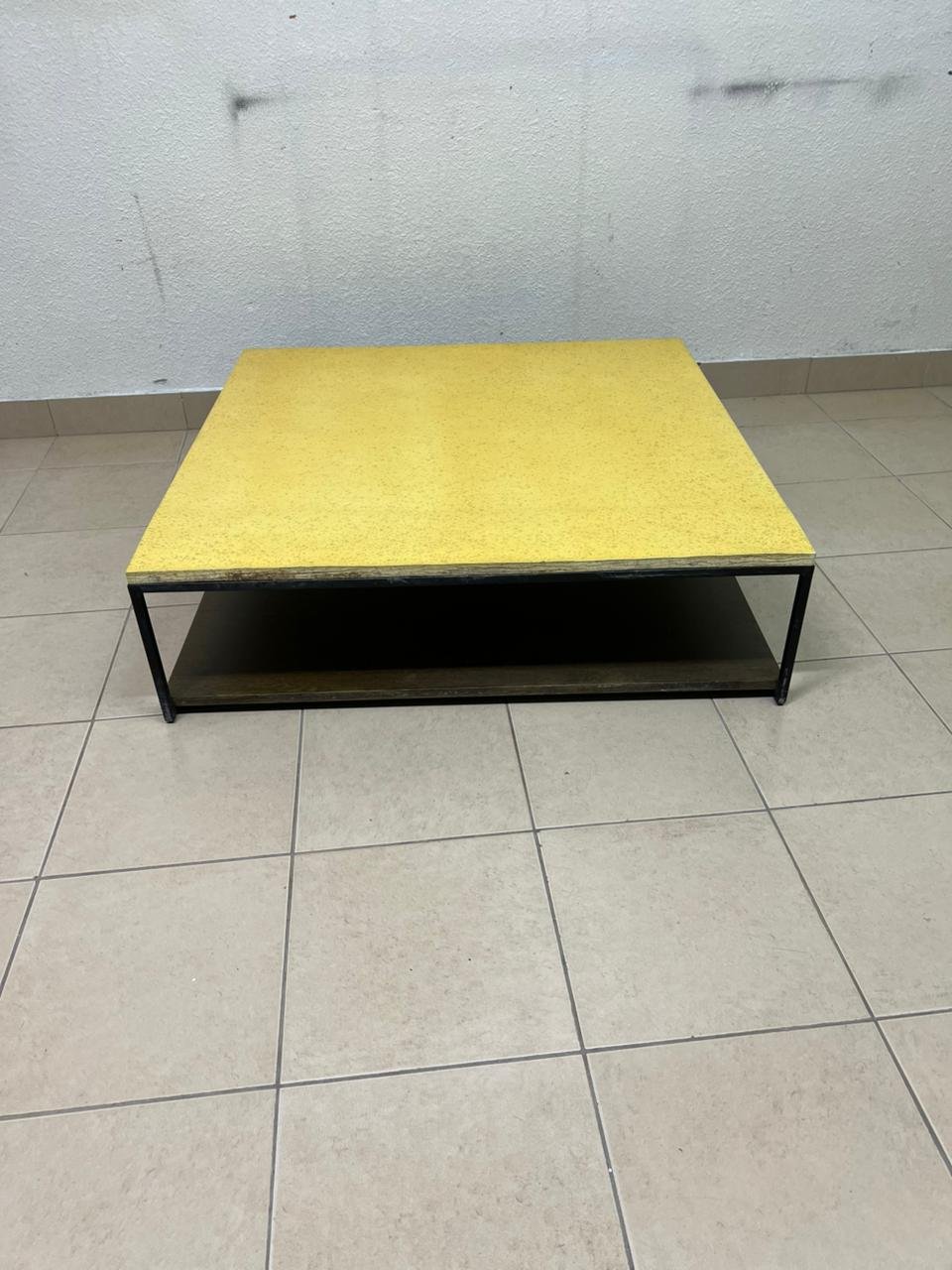 This is a square coffee table with an industrial design, featuring a black metal frame, a black pull-out drawer or lower shelf, and a light yellow wooden top. - Image 2