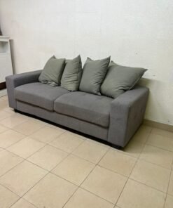 A gray fabric sofa with three seats and a rectangular design, equipped with four olive green back cushions.