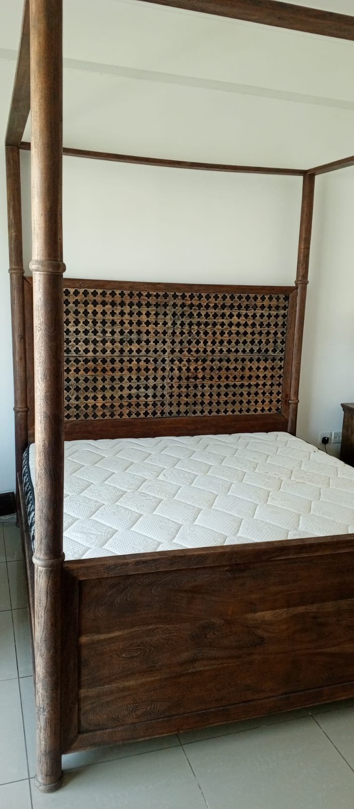 A bed, a piece of wooden furniture with a four-poster design and a headboard decorated with raised geometric patterns, along with a mattress. - Image 2