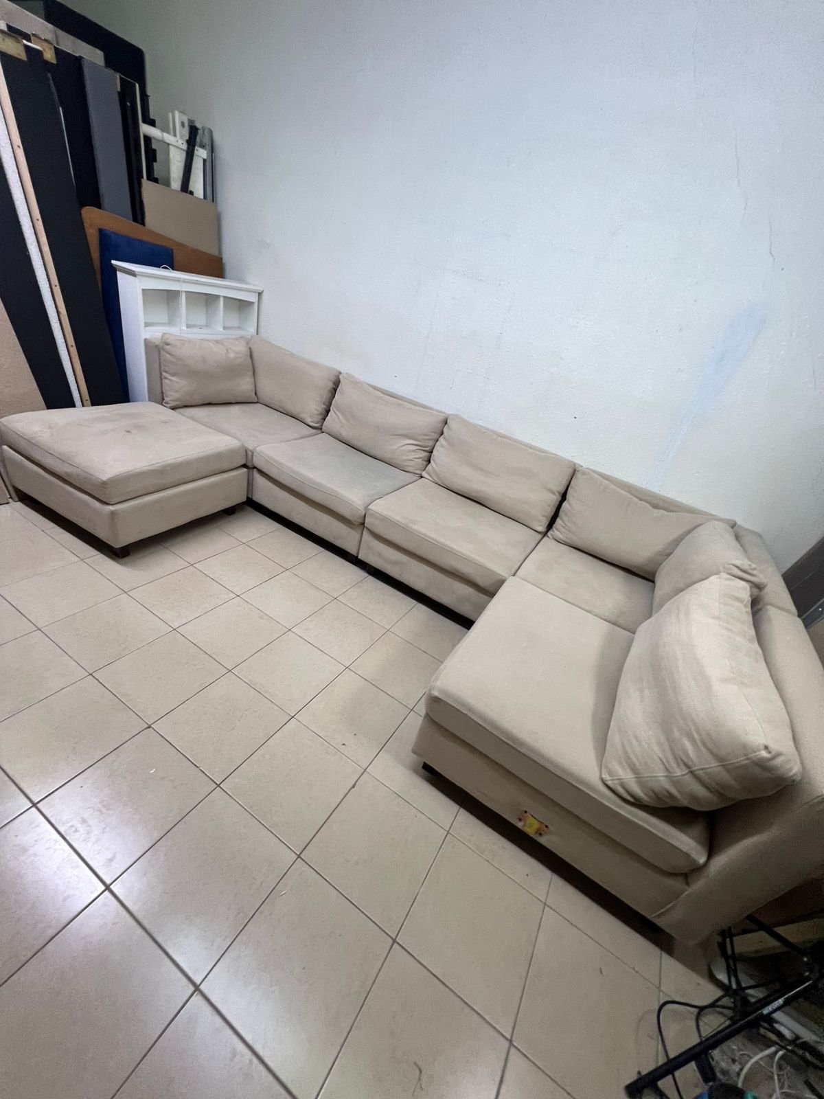 A spacious, modern, U-shaped sectional sofa in a calm beige color with a footrest.