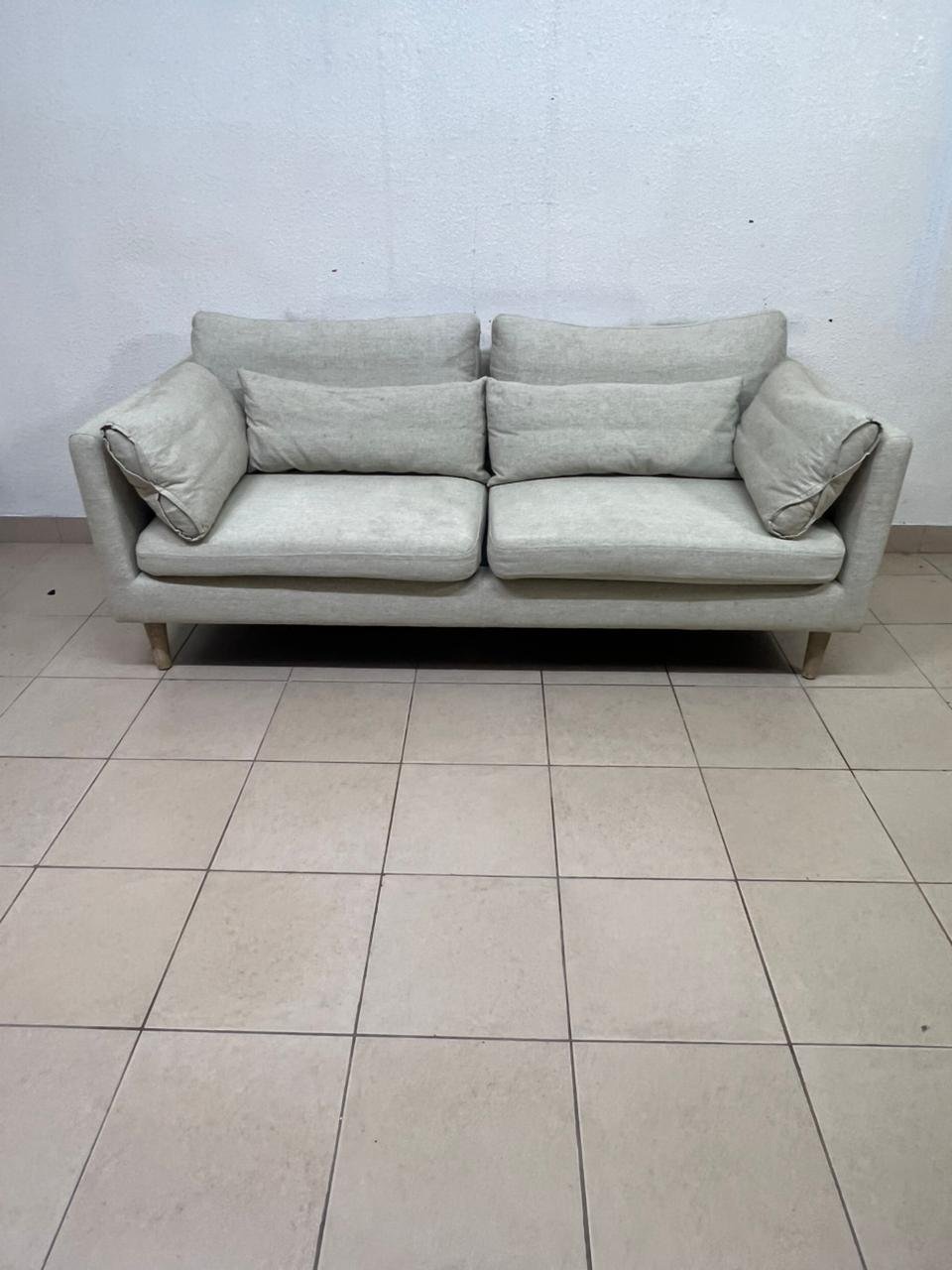 A spacious light beige fabric sofa with back cushions and additional long, square cushions. - Image 3