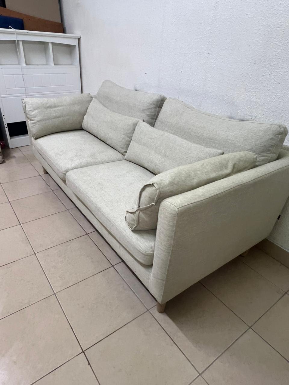 A spacious light beige fabric sofa with back cushions and additional long, square cushions. - Image 4