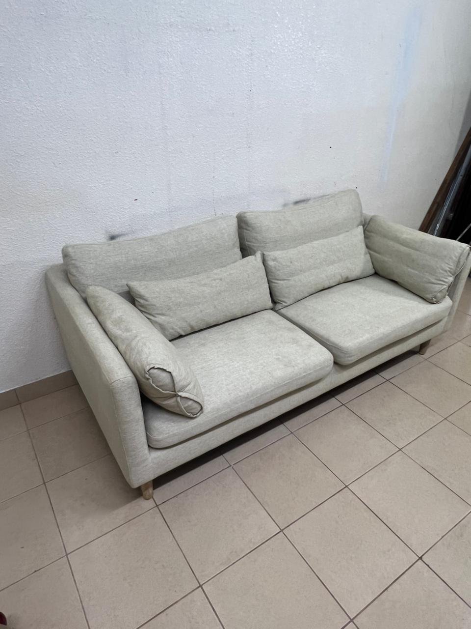 A spacious light beige fabric sofa with back cushions and additional long, square cushions. - Image 6