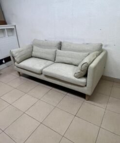 A spacious light beige fabric sofa with back cushions and additional long, square cushions.