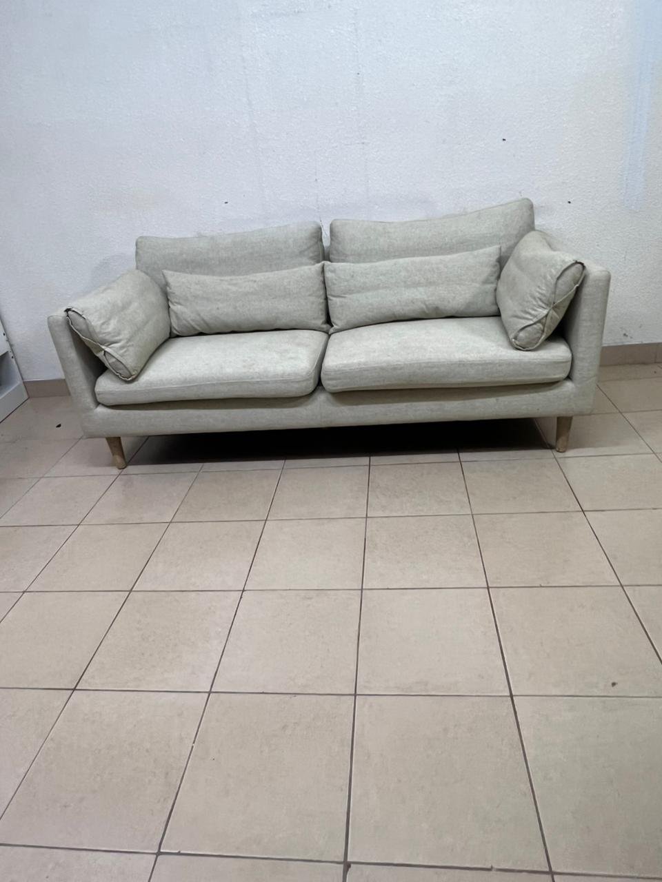 A spacious light beige fabric sofa with back cushions and additional long, square cushions. - Image 9