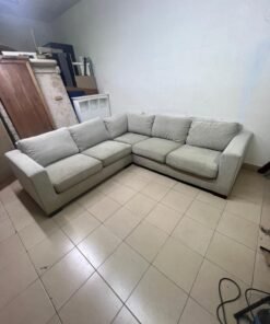 A corner sofa with a modern design (L-shaped) and upholstered in light beige or calm gray fabric.