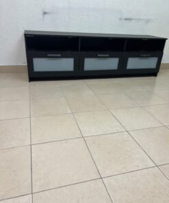 The television unit shown in the picture is a modern black TV stand with three drawers featuring opaque glass fronts and open shelves for appliances. - Image 2