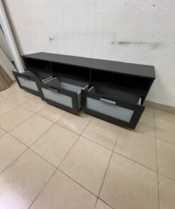 The television unit shown in the picture is a modern black TV stand with three drawers featuring opaque glass fronts and open shelves for appliances. - Image 4