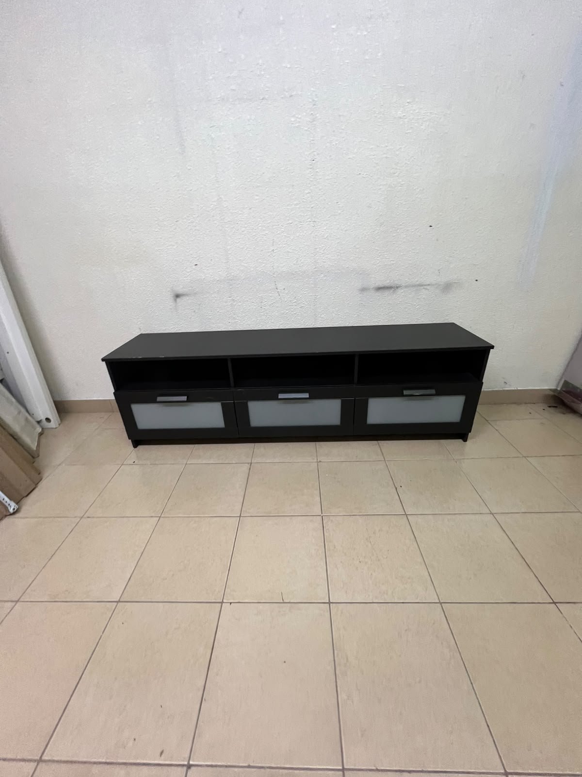 The television unit shown in the picture is a modern black TV stand with three drawers featuring opaque glass fronts and open shelves for appliances. - Image 6