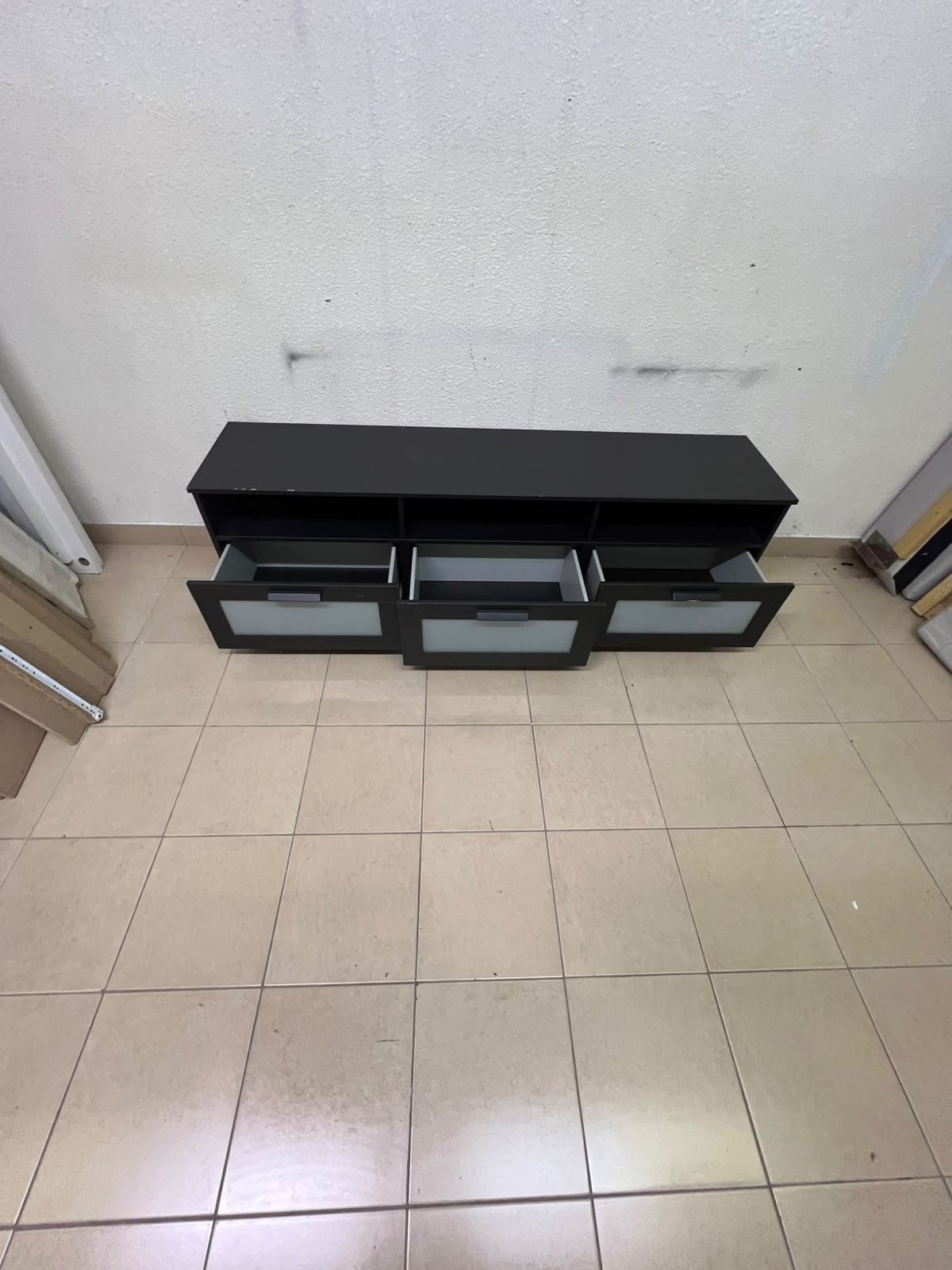 The television unit shown in the picture is a modern black TV stand with three drawers featuring opaque glass fronts and open shelves for appliances. - Image 8