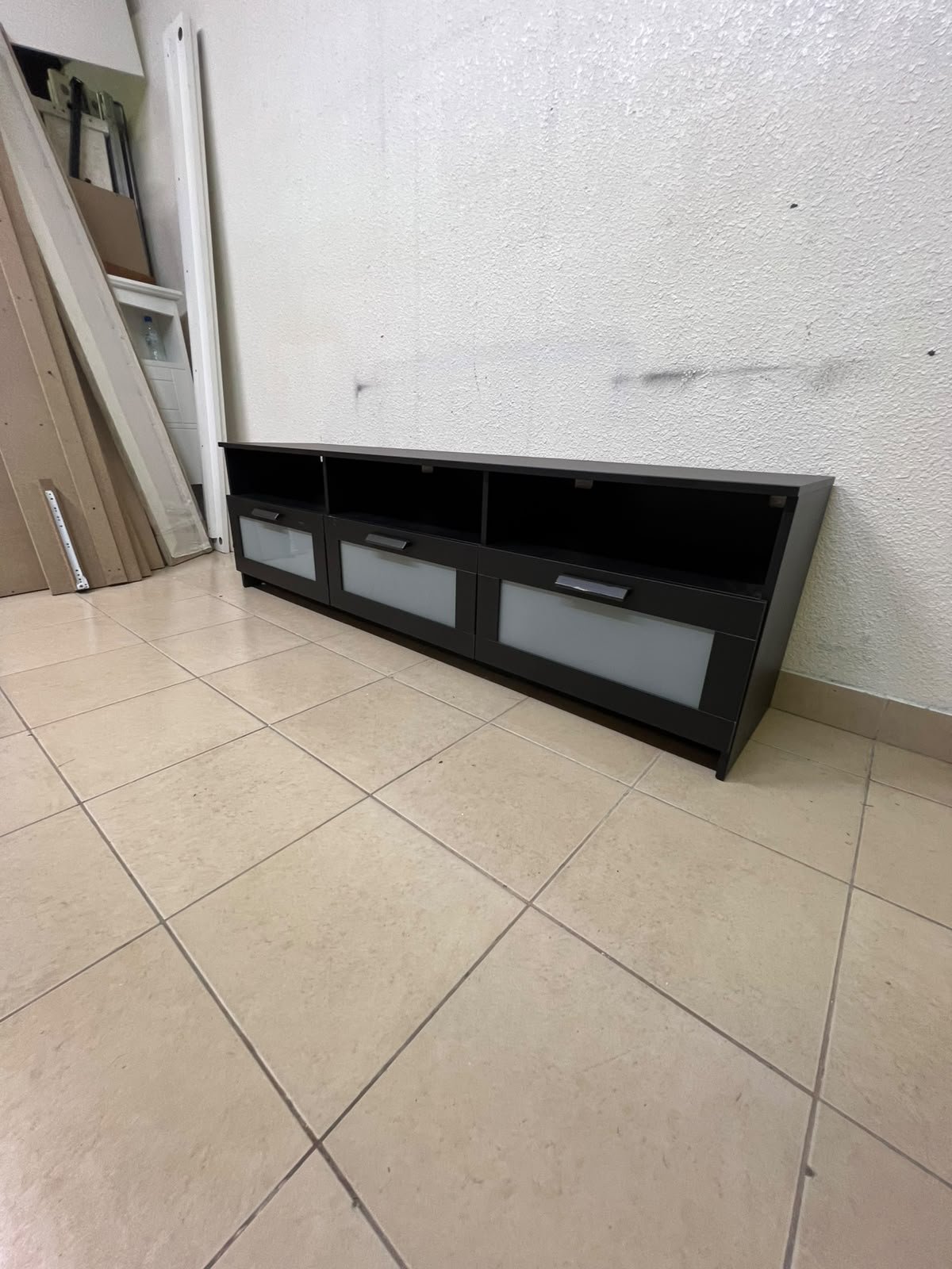 The television unit shown in the picture is a modern black TV stand with three drawers featuring opaque glass fronts and open shelves for appliances. - Image 10