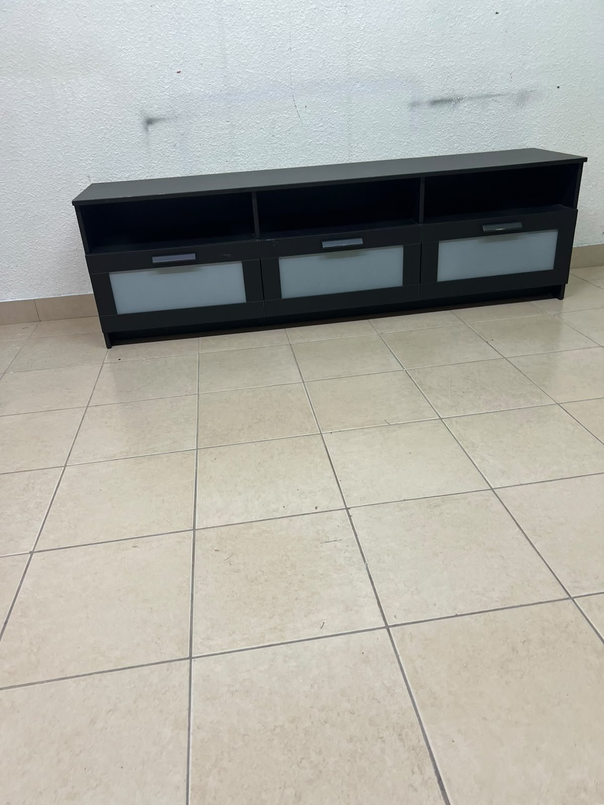 The television unit shown in the picture is a modern black TV stand with three drawers featuring opaque glass fronts and open shelves for appliances. - Image 11