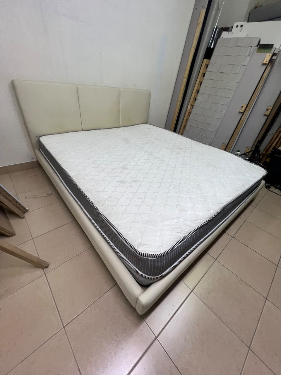 Double bed with a light beige upholstered design, featuring a split headboard and a white mattress with gray and black edges. - Image 3