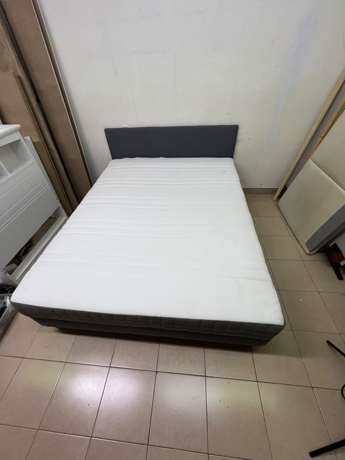 A gray upholstered bed frame with a white mattress and blanket, or a dark gray mattress on the side. - Image 3