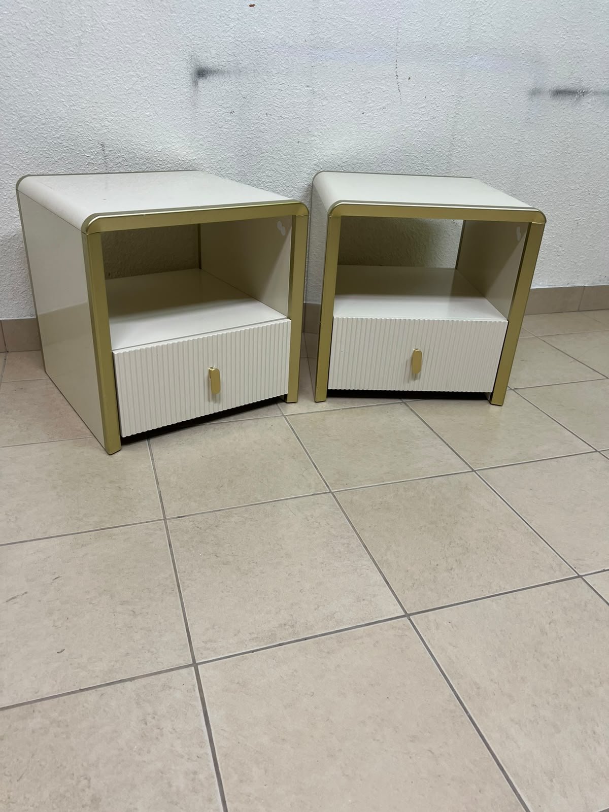 The image shows two modern bedside tables in a creamy white finish, featuring gold frames and details, as well as ribbed drawer fronts (from Home Centre). - Image 10