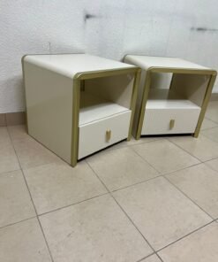 The image shows two modern bedside tables in a creamy white finish, featuring gold frames and details, as well as ribbed drawer fronts (from Home Centre). - Image 3
